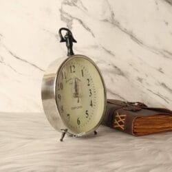 Angled view of the silver desk and hanging clock, highlighting its polished aluminum casing and sturdy construction.