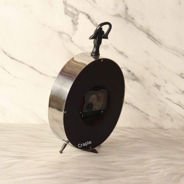 The back of the silver desk clock, showing the battery mechanism and the deep, polished aluminum frame.