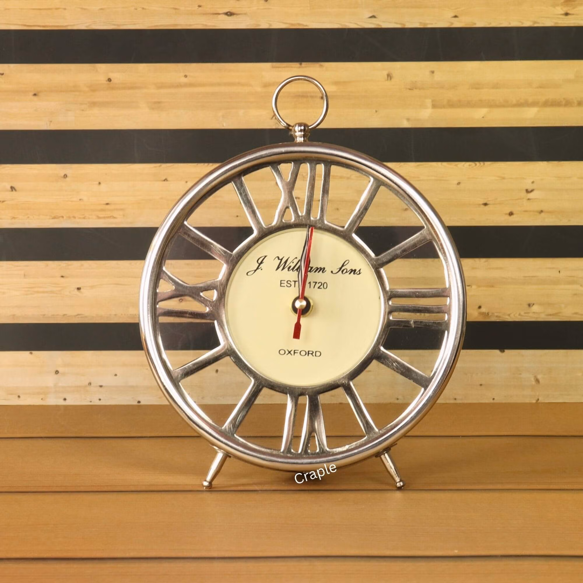 A round silver skeleton mantel clock with a nickel finish, an off-white dial, and a Roman numeral frame.