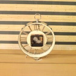 The back of the silver skeleton desk clock, showing the central quartz battery movement.