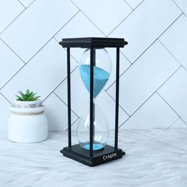 A tall black hourglass with light blue sand, shown from a slight angle against a white background.