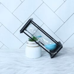 The sky blue sand hourglass tilted at a dynamic angle, with sand flowing between the bulbs.