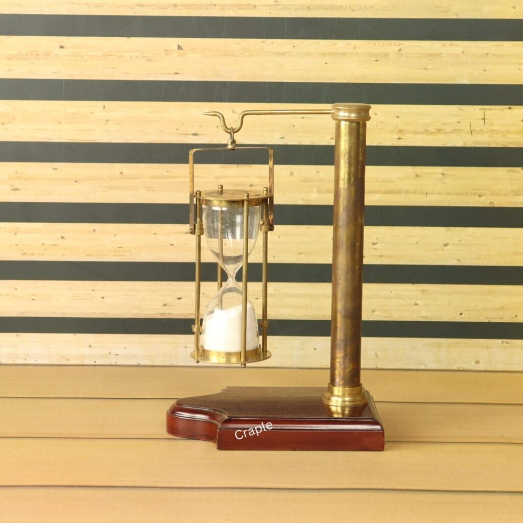 A vintage-style 5-minute hourglass with white sand, hanging from an antique brass stand with a wooden base.