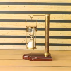 A vintage-style 5-minute hourglass with white sand, hanging from an antique brass stand with a wooden base.