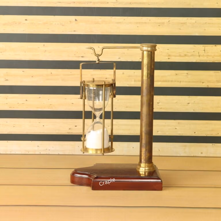 A vintage-style 5-minute hourglass with white sand, hanging from an antique brass stand with a wooden base.
