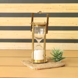 The detachable brass 5-minute hourglass timer with white sand, shown sitting on a surface.