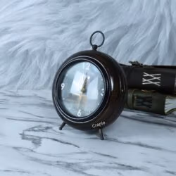 The antique wooden table clock displayed on a marble desk next to vintage books.