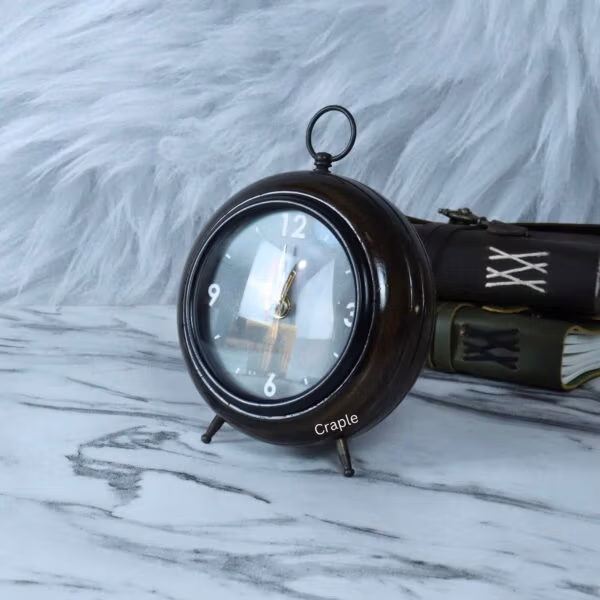 The antique wooden table clock displayed on a marble desk next to vintage books.
