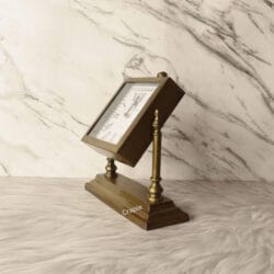 The square antique brass clock tilted upwards on its stand to show its adjustable viewing angle.