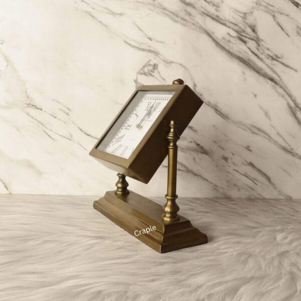 The square antique brass clock tilted upwards on its stand to show its adjustable viewing angle.