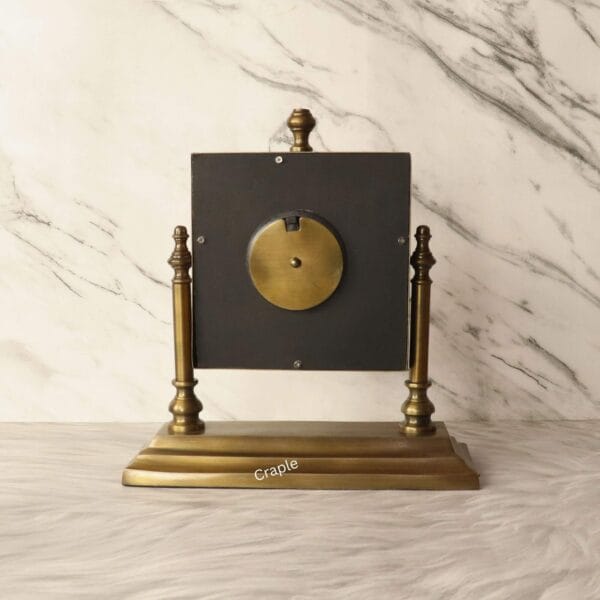 The back of the square tilting clock, showing the mechanism cover and the solid brass-finished stand.