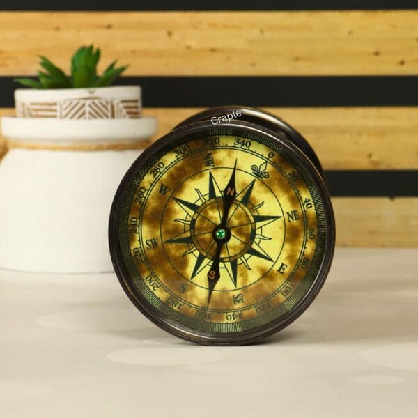 Close-up of the vintage-style compass integrated into the base of the antique brass hourglass.