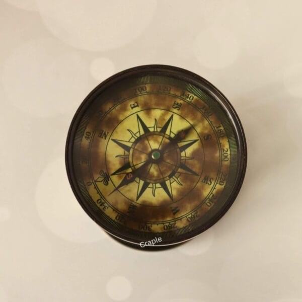 Top-down view of the antique compass dial on the brass hourglass, showing the aged compass rose design.