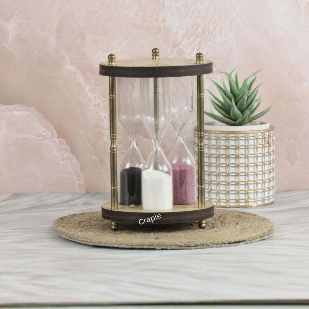 A unique 3-in-1 hourglass with a wooden frame and antique brass pillars, featuring timers with black, white, and pink sand.