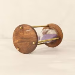 Close-up of the rich-grained wooden base of the vintage hourglass, detailing the brass hardware.