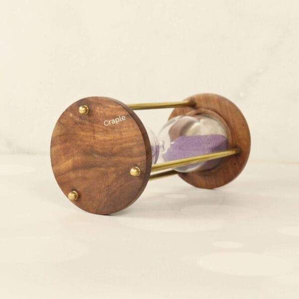 Close-up of the rich-grained wooden base of the vintage hourglass, detailing the brass hardware.