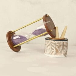 The 5-minute purple sand hourglass used as a stylish desktop accessory next to a pen holder.