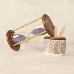 The 5-minute purple sand hourglass used as a stylish desktop accessory next to a pen holder.