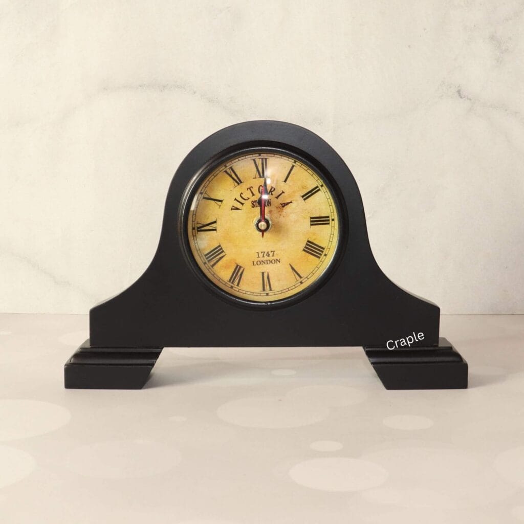 Vintage Victoria-style mantel clock with a black antique finish, a round aged-yellow dial, and classic Roman numerals.