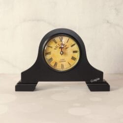 Vintage Victoria-style mantel clock with a black antique finish, a round aged-yellow dial, and classic Roman numerals.