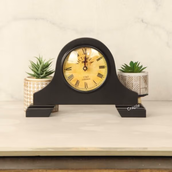 The vintage-style black mantel clock sitting on a tabletop, showing its elegant design in a home setting.