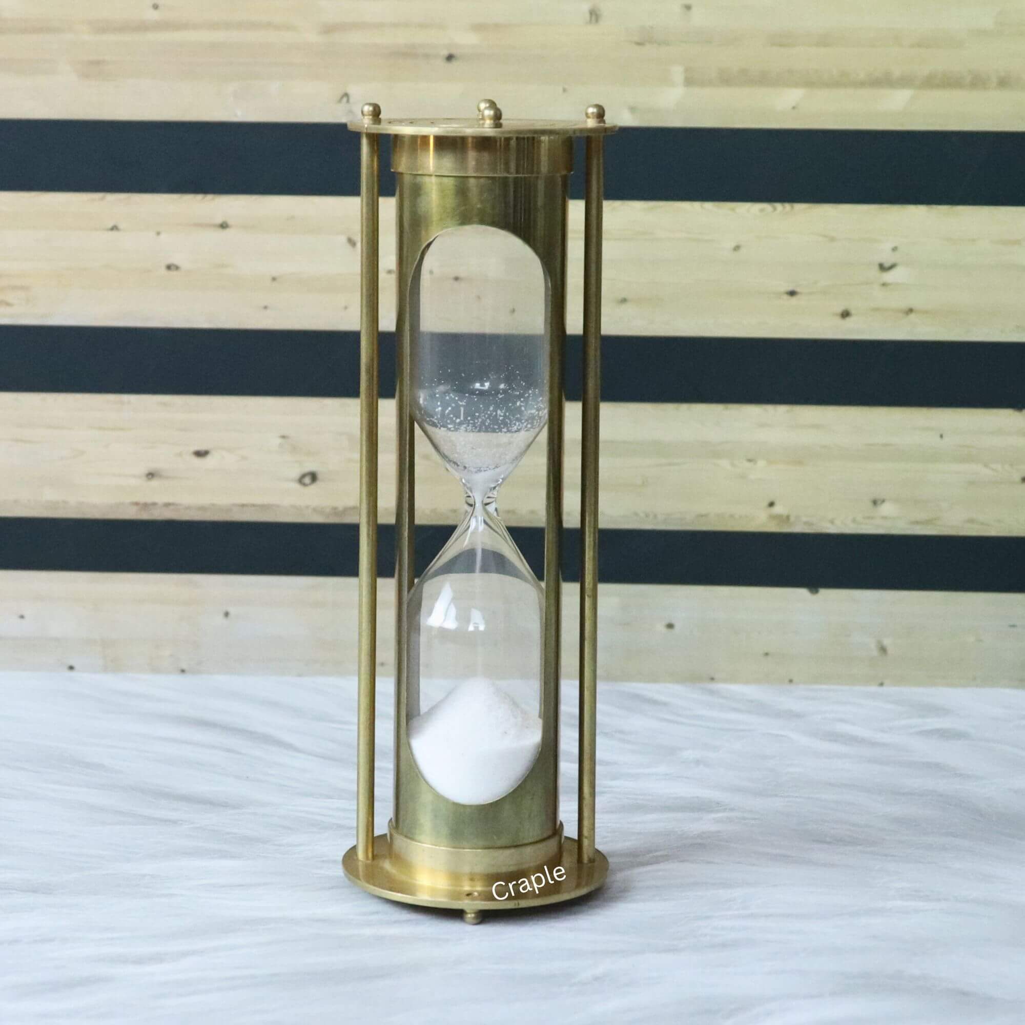 Vintage brass 5-minute hourglass-1 Vintage brass 5-minute hourglass with a shiny finish and pillar design, showing white sand flowing through the glass.