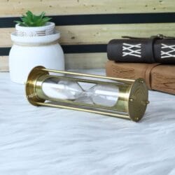 The decorative brass hourglass displayed on its side, perfect for a nautical or vintage-themed office.