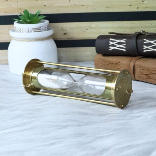 The decorative brass hourglass displayed on its side, perfect for a nautical or vintage-themed office.