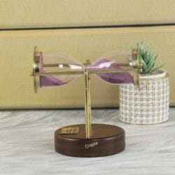 The brass and wood hourglass resting horizontally, demonstrating its swivel and pivot design.