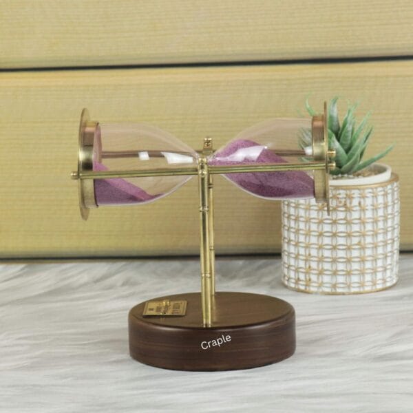 The brass and wood hourglass resting horizontally, demonstrating its swivel and pivot design.
