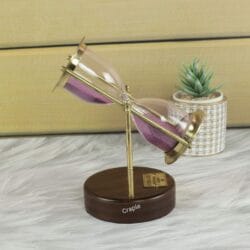 A Royal Navy style hourglass with pink sand, swiveling on its shiny brass stand above a wooden base.