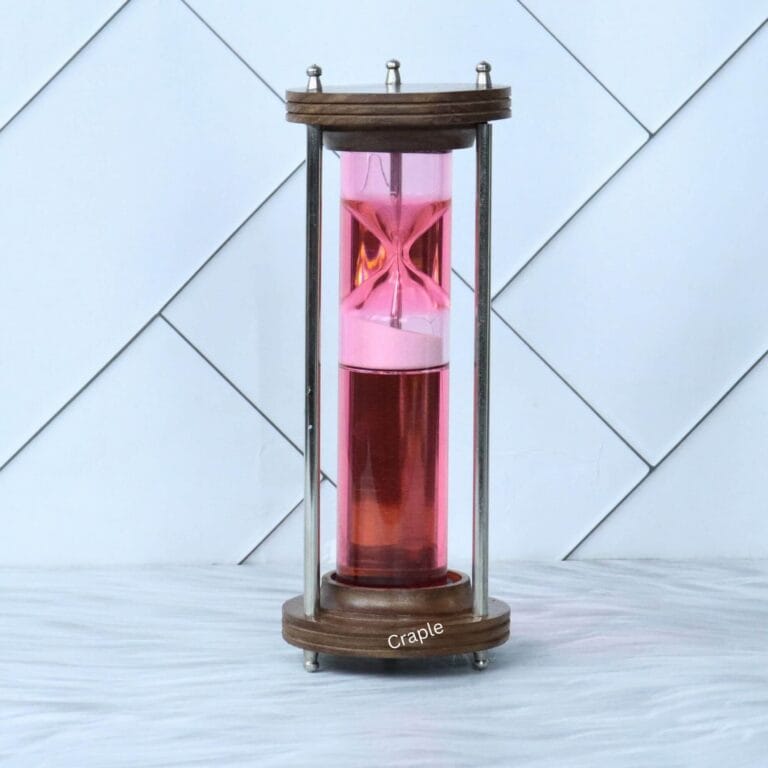 A modern liquid hourglass with a wood and brass frame, featuring a floating pink timer mechanism in red liquid.