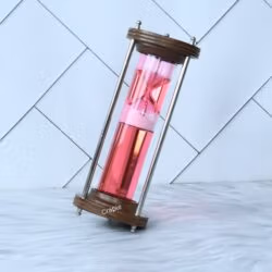The wood and brass liquid hourglass tilted at an angle, showing the pink timer element floating within the red liquid.