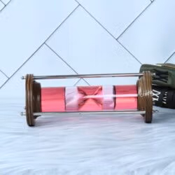 The decorative liquid sand timer lying horizontally, showcasing the wood and brass construction.