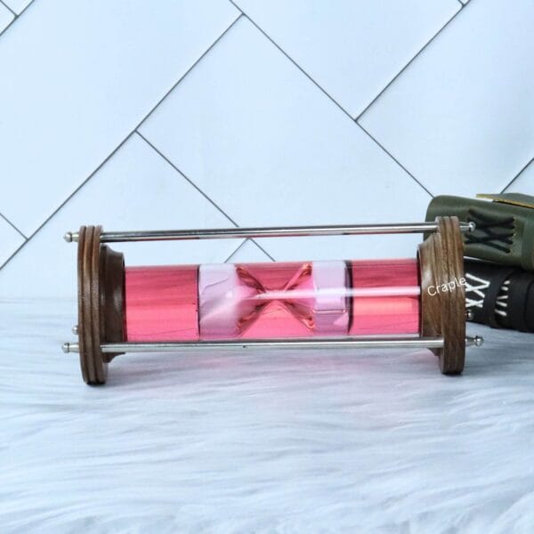 The decorative liquid sand timer lying horizontally, showcasing the wood and brass construction.