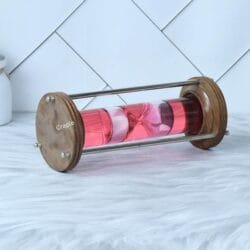 The wood and brass hourglass lying on its side, showing the detail of the polished wooden base and brass rods.