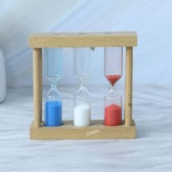 Angled view of the triple sand timer, with red sand flowing through the 1-minute hourglass.