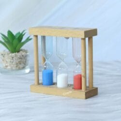 Handmade wooden triple sand timer with 1, 3, and 5-minute hourglasses, shown from an angle to highlight its natural wood construction.