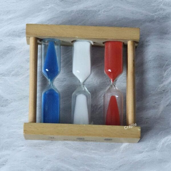 Top-down view of the red, white, and blue sand hourglasses set within the light wood frame.